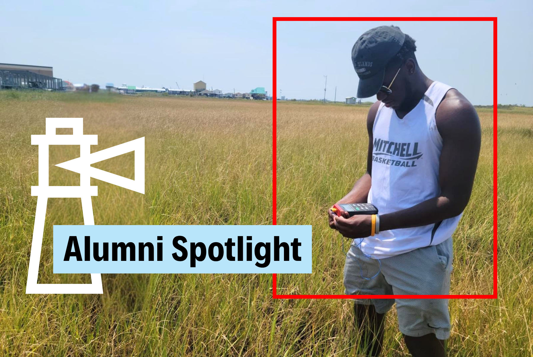 A man wearing a baseball hat and Mitchell Basketball shirt stand on a coastline conducting a scientific study