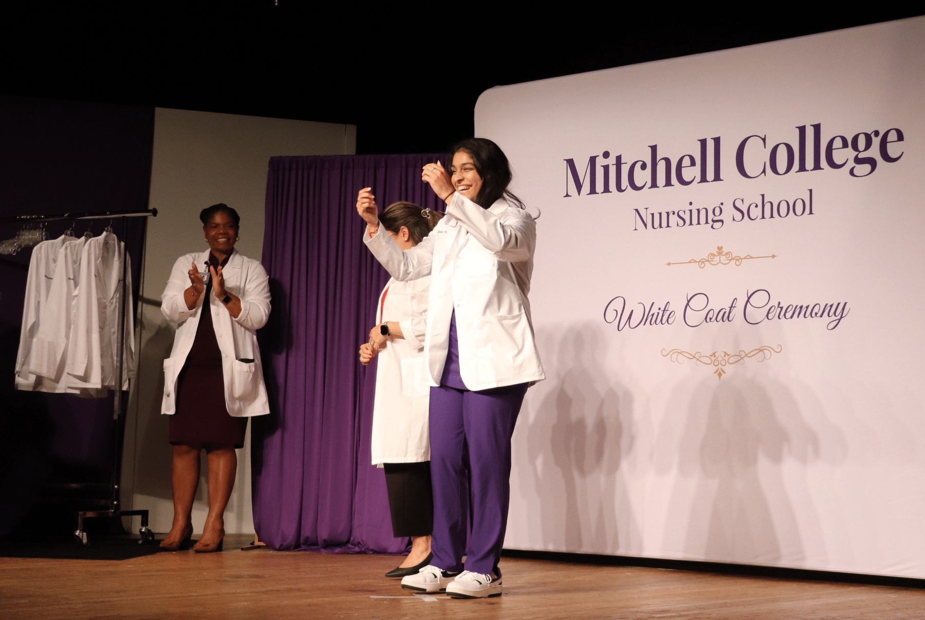 Nursing_White_Coat_Ceremony A nursing student wears a white coat given to her by a faculty during a white coat ceremony.